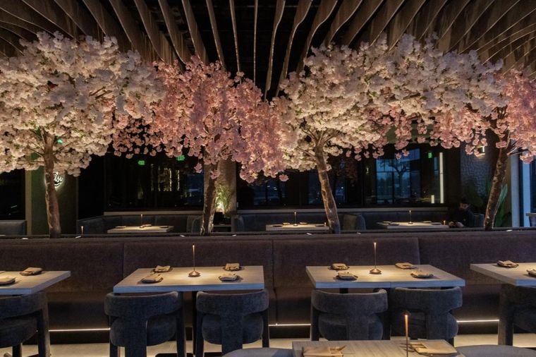 The Kasi dining room at night, banquettes set under illuminated cherry blossom trees